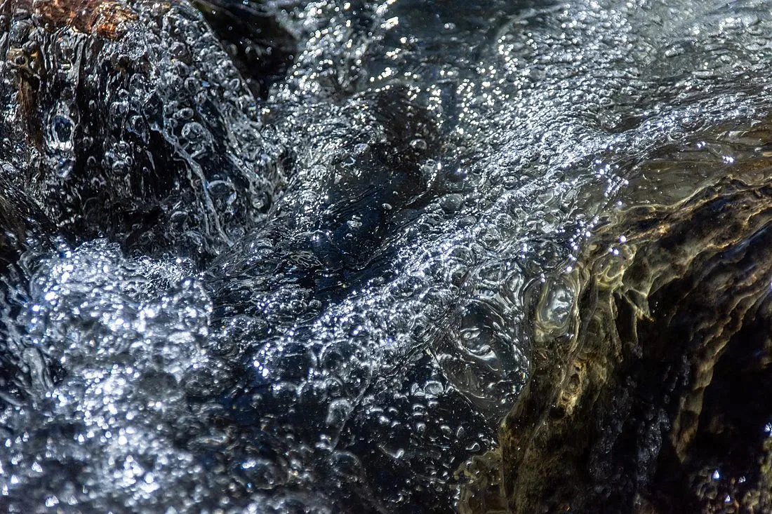 a river with a diagonal line of rising bubbles across its surface