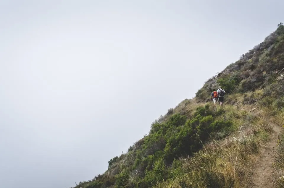 an EMT hiking up a mountain trail carrying a medical pack