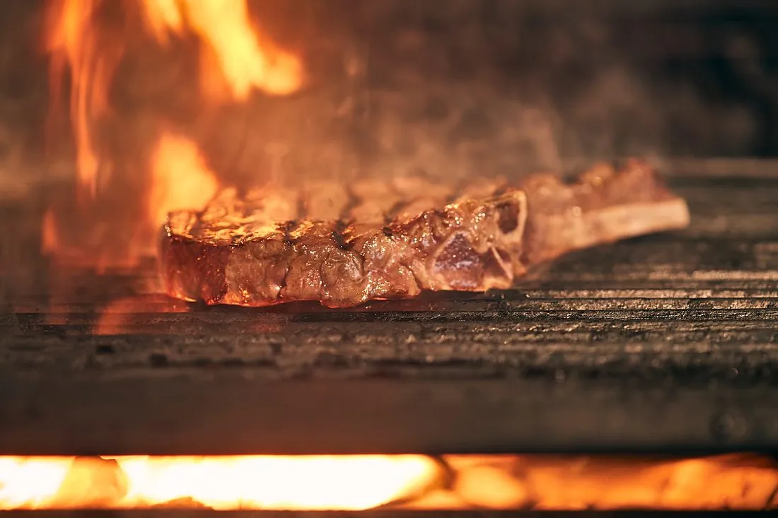 a chef searing a steak in a restaurant kitchen